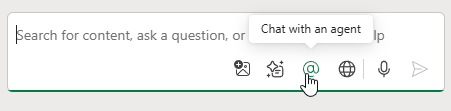 Новый стиль панели Copilot. Под полем ввода пять иконок. Третья — знак @. При наведении всплывает подсказка 'Chat With An Agent'.